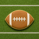 Football-shaped cookie on a green field background from a 5.5 inch Eye or Football Metal Cookie Cutter