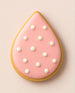 Decorated cookie shaped like a teardrop with pink icing and white pearls on a light background from a 2 inch Tear Drop Rain Flower Petal Metal Cookie Cutter