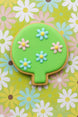 Decorative cookie with green top and floral designs on a floral background from a 4 inch Leaf Tree Shrub Metal Cookie Cutter