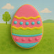 Colorful Easter egg-shaped cookie on a green grass background with a blue sky from a 4 inch Easter Egg Metal Cookie Cutter