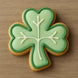 Shaped cookie with green icing and white accents on a wooden surface from a 1.75 inch Mini Shamrock Metal Cookie Cutter