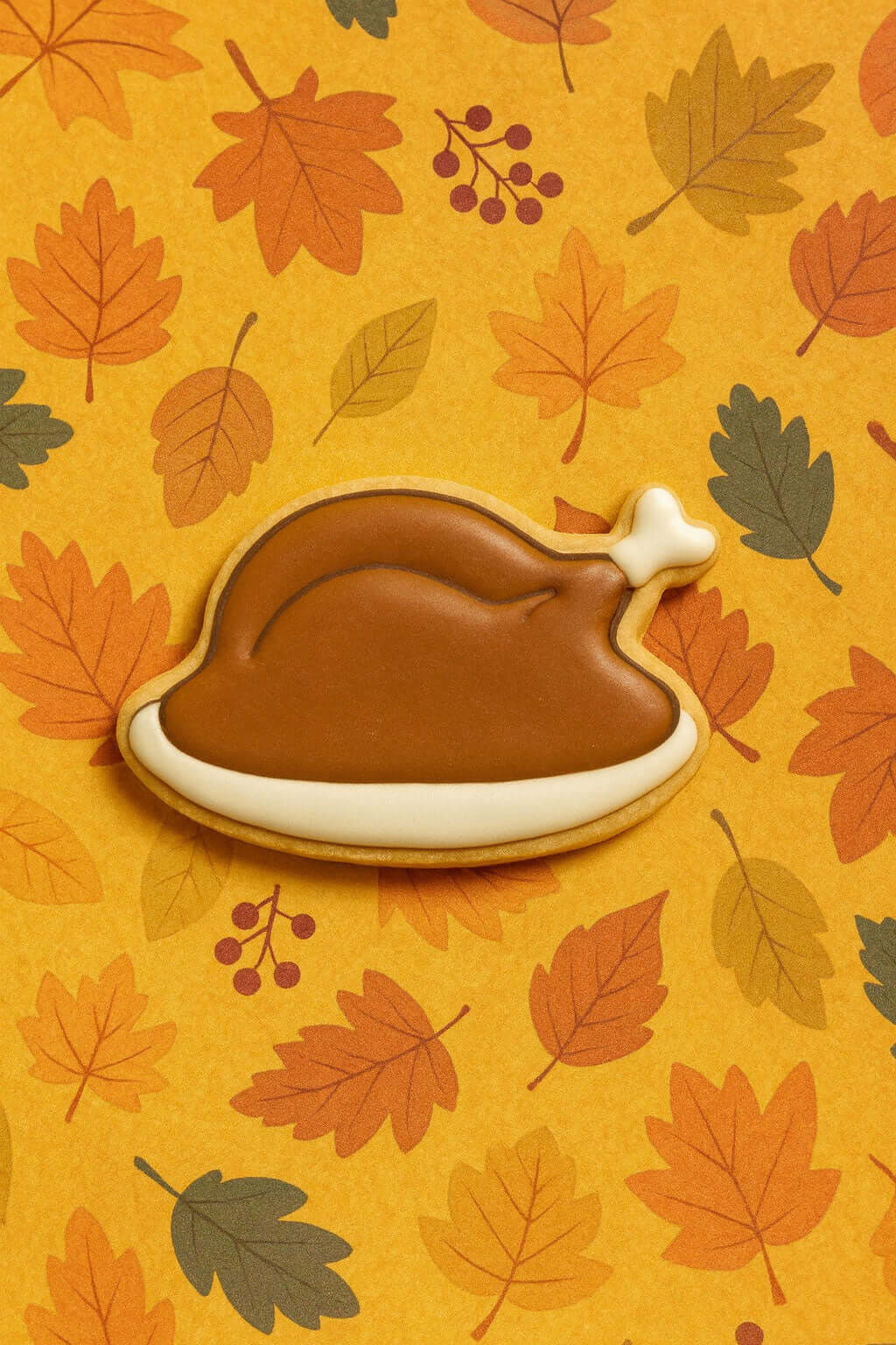 Cookie shaped like a roasted turkey on an autumn leaf pattern from a 2.25 inch Mini Turkey Dinner Metal Cookie Cutter