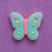 Butterfly-shaped cookie with pink, blue, and yellow icing on a purple background from a 2 inch Mini Butterfly Metal Cookie Cutter