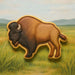Cookie-shaped bison on a grassy field with mountains in the background from a 2.25 inch Mini Buffalo Metal Cookie Cutter