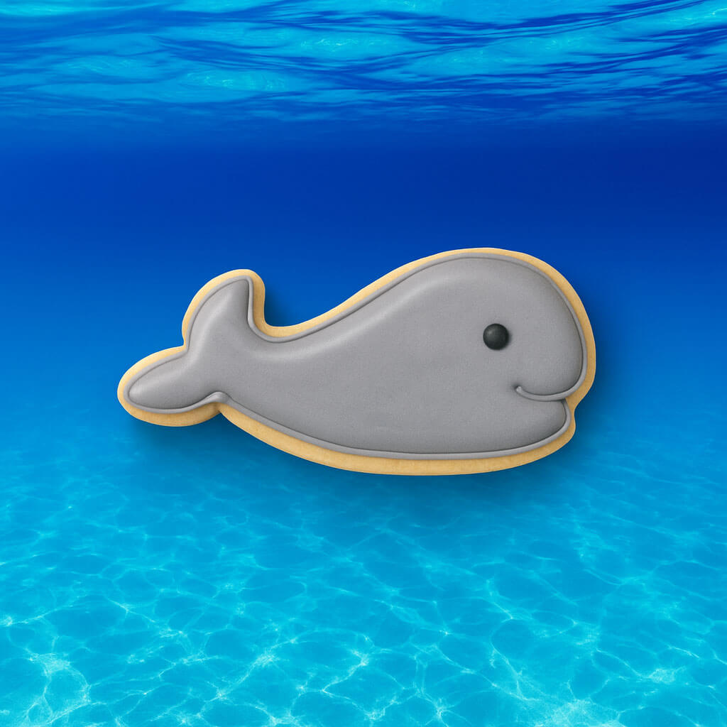 Whale-shaped cookie on a blue water background from a 2.25 inch Mini Whale Metal Cookie Cutter