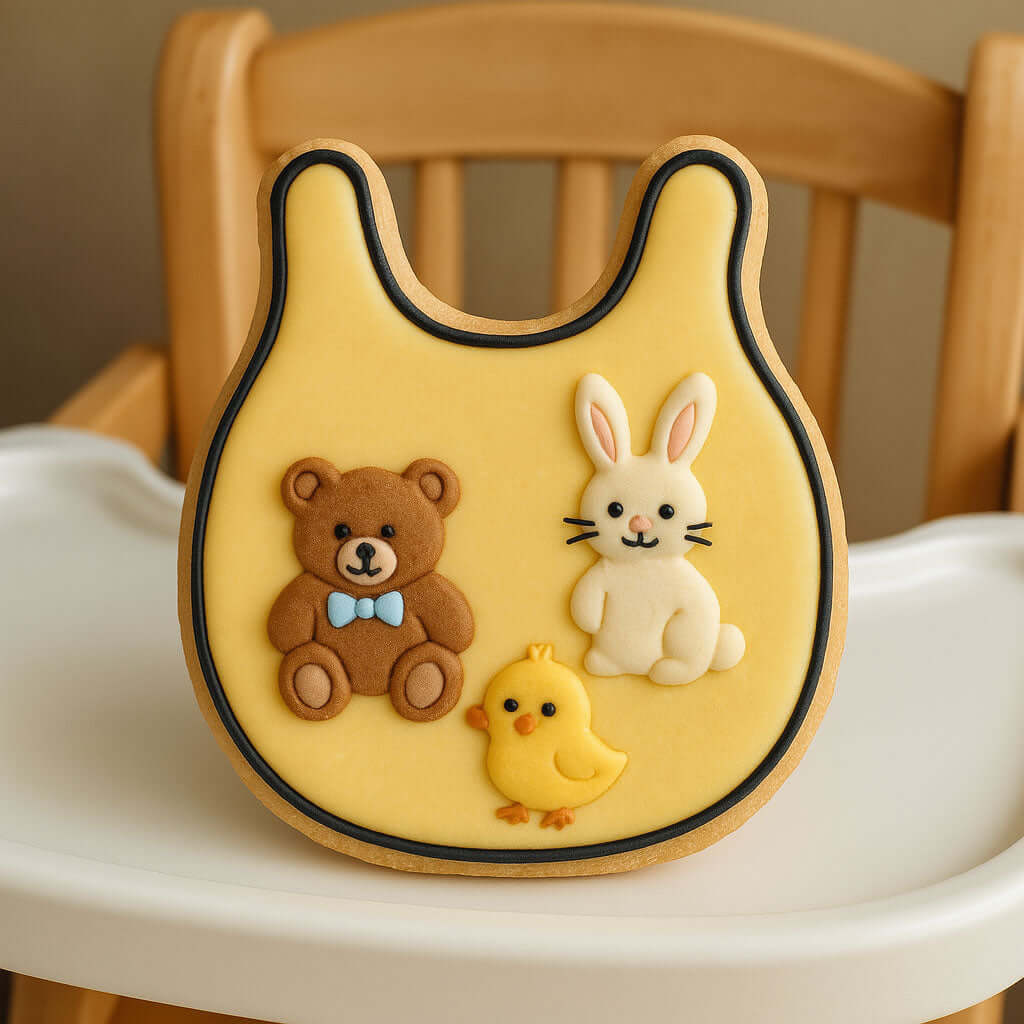 Yellow bib with teddy bear, rabbit, and chick designs on a high chair from a 2 inch Mini Baby Bib Metal Cookie Cutter