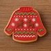 Red sweater-shaped cookie with reindeer and snowflake decorations on a wooden surface from a 2 inch Mini Ugly Sweater Metal Cookie Cutter