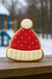 Decorative cookie shaped like a Santa hat on a wooden surface with a blurred outdoor background from a 2 inch Mini Winter Hat Metal Cookie Cutter