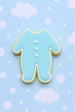 Cookie shaped like a baby footie pajamas on a light blue background with white dots from a  2 inch Mini Footie Pajamas Metal Cookie Cutter