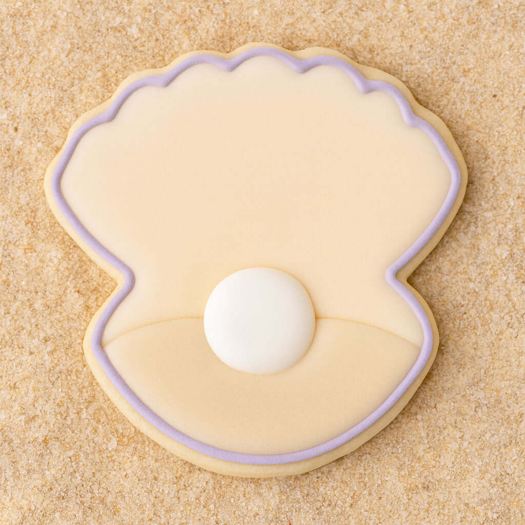 Cookie shaped like a seashell with a pearl on a sandy background from a 2 inch Mini Oyster Clam Shell with Pearl Metal Cookie Cutter