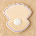 Cookie shaped like a seashell with a pearl on a sandy background from a 2 inch Mini Oyster Clam Shell with Pearl Metal Cookie Cutter