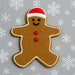 Gingerbread man cookie with a red hat and buttons on a gray background with snowflakes from a 5 inch Gingerbread Boy Metal Cookie Cutter