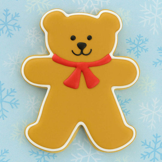 Decorative bear cookie with a red bow on a blue background with snowflakes from a 4 inch Teddy Bear Metal Cookie Cutter