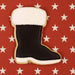 Cookie shaped like a black boot with white top on a red background with white stars from a 4 inch Santa Boot Metal Cookie Cutter