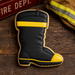 Cookie shaped like a firefighter boot with black and yellow colors on a wooden surface made from a 4 inch Santa or Fireman Boot Metal Cookie Cutter