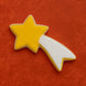 Star-shaped cookie with a white trail on an orange background from a 4 inch Shooting Star Metal Cookie Cutter