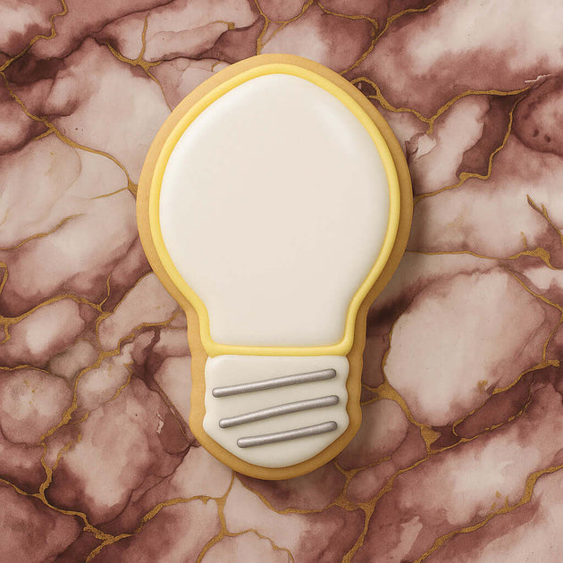 4.5 inch Light Bulb Metal Cookie Cutter shaped cookie on marble surface background.