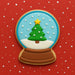Decorative cookie shaped like a snow globe with a Christmas tree on a red background from a 3.5 inch Snow Globe Metal Cookie Cutter