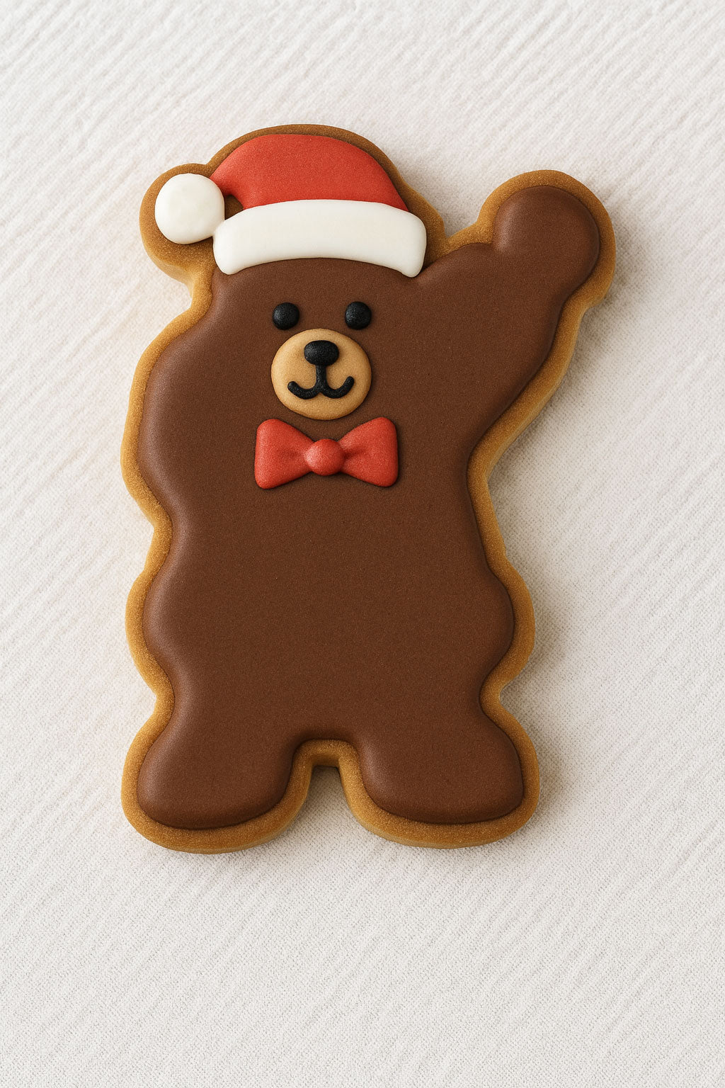 Brown bear-shaped cookie with a red bow tie and Santa hat on a white textured background from a 3.75 inch Waving Santa Metal Cookie Cutter