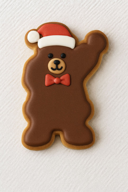 Brown bear-shaped cookie with a red bow tie and Santa hat on a white textured background from a 3.75 inch Waving Santa Metal Cookie Cutter