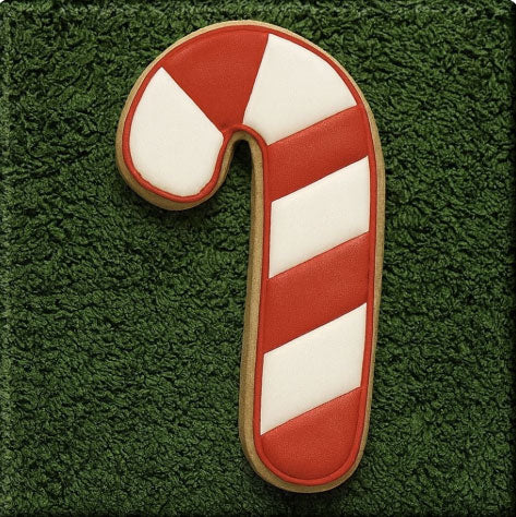 Candy cane-shaped cookie on a green textured background from a 5 inch Candy Cane Metal Cookie Cutter