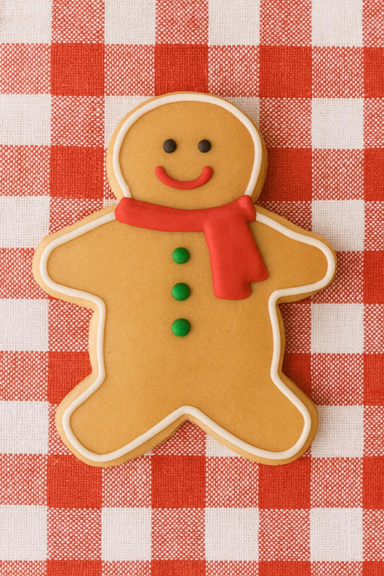 Gingerbread man cookie with a red scarf on a red and white checkered tablecloth