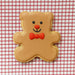 Gingerbread bear cookie with a red bow tie on a red and white checkered background from a 3 inch Teddy Bear Metal Cookie Cutter