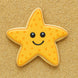 Star-shaped cookie with a smiley face on a sandy background from a 3.25 inch Folk Star or Starfish Metal Cookie Cutter