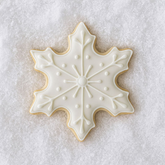 Decorative snowflake cookie with white icing on a textured white background from a 3 inch Snowflake Metal Cookie Cutter