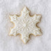Decorative snowflake cookie with white icing on a textured white background from a 3 inch Snowflake Metal Cookie Cutter