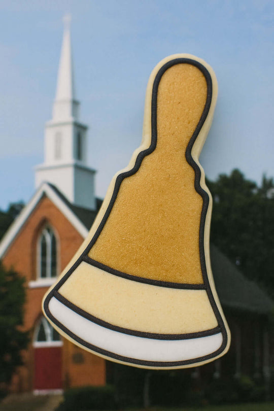 Decorative hand bell-shaped object with a church in the background