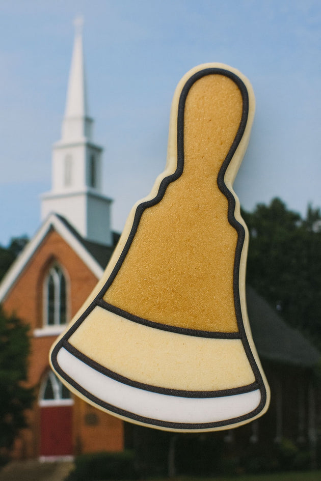 Decorative hand bell-shaped object with a church in the background