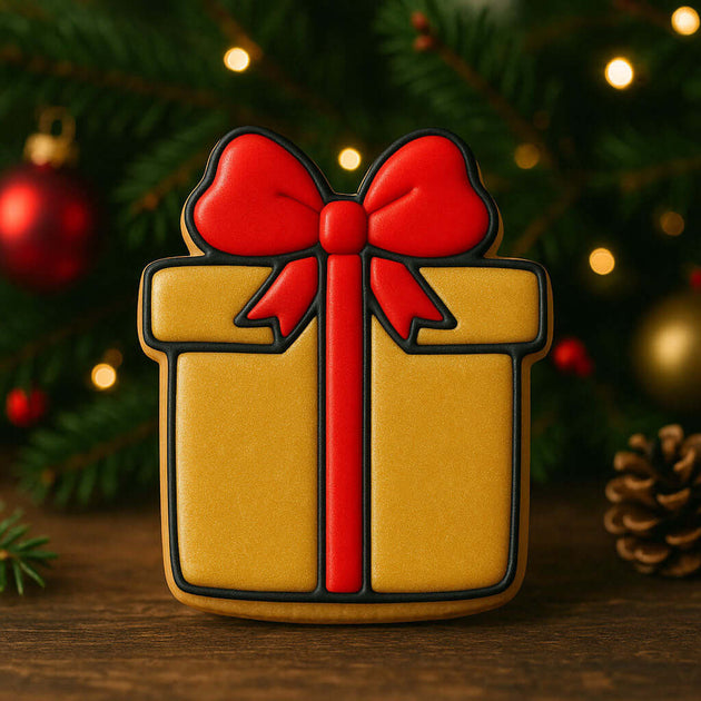 Gift-shaped cookie with a red bow on a wooden surface with Christmas decorations in the background from a 4 inch Present Metal Cookie Cutter
