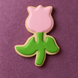 3 inch Tulip Metal Cookie Cutter shaped cookie decorated with pink and green icing on a purple background.