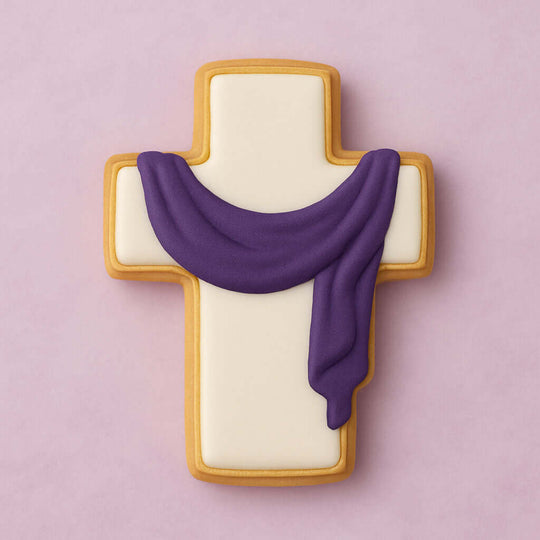 Decorative cookie shaped like a cross with a purple scarf on a pink background from a 2.75 inch Cross Metal Cookie Cutter