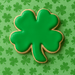 3 inch Clover Metal Cookie Cutter shaped green cookie on a shamrock patterned background for St. Patrick's Day.