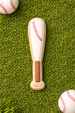 4.5 inch Baseball Bat Metal Cookie Cutter shaped cookie on grass with baseballs, perfect for sports-themed baking.