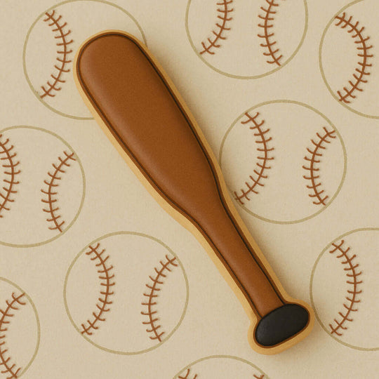 Cookie cutter shaped like a baseball bat on a background with baseball patterns from a 4.5 inch Baseball Bat Metal Cookie Cutter