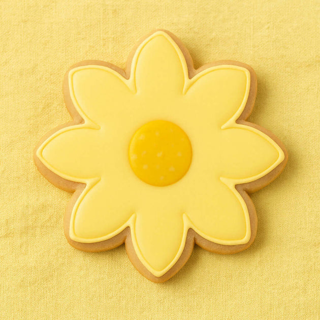 flower-shaped cookie with yellow icing on a yellow background from a 3.5 inch Daisy Flower Metal Cookie Cutter