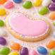 Heart-shaped cookie with pink icing and colorful sprinkles on a bed of jelly beans. from a 3.5 inch Jellybean Metal Cookie Cutter