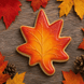 Maple leaf-shaped cookie on a bed of autumn leaves from a 3 inch Maple Leaf Metal Cookie Cutter