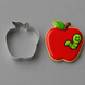 An apple-shaped metal cookie cutter shown next to a decorated apple-shaped sugar cookie with a red icing body, green leaf, brown stem, and a smiling green caterpillar from a 3 inch Apple Metal Cookie Cutter