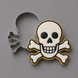 A pirate skull and crossbones cookie cutter set on a neutral gray background, showing both the metal cutter and the shaped cookie with white icing, black details, and a gold border from a 3.25 inch Skull and Crossbones Metal Cookie Cutter