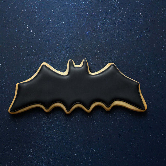 4 inch Flying Bat Metal Cookie Cutter shaped bat cookie decorated in black icing on a starry background.