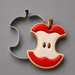 A metal apple-shaped cookie cutter positioned behind a decorated sugar cookie shaped like an apple core, shown on a smooth gray background from a 4 inch Apple Core Metal Cookie Cutter