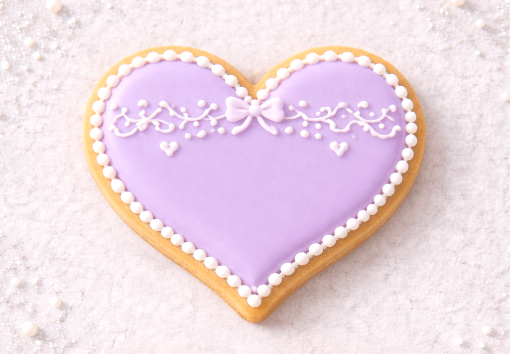 Heart-shaped cookie with purple icing and white decorations on a light background from a 1.75 inch Mini Heart Metal Cookie Cutter