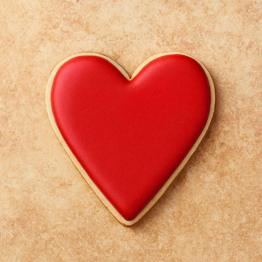 Heart-shaped cookie with red icing on a beige background