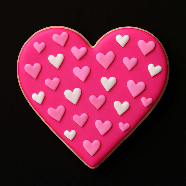 Heart-shaped cookie with pink and white heart decorations on a black background from a 2.25 inch Heart Metal Cookie Cutter