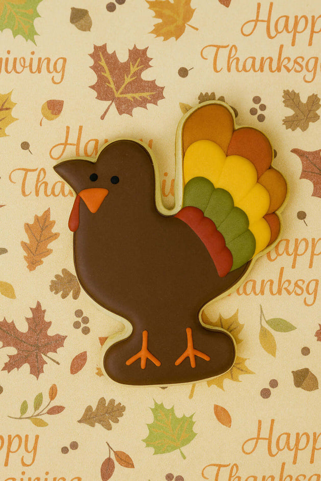 3.5 inch Turkey or Rooster Metal Cookie Cutter shaped cookie on a Thanksgiving themed background.