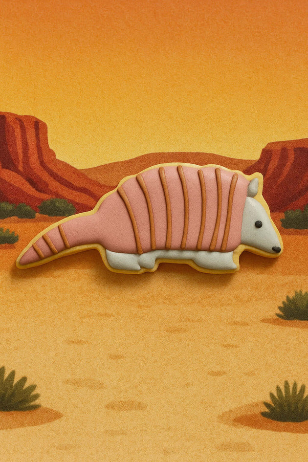 5 inch Armadillo Metal Cookie Cutter shaped pink cookie on desert background.